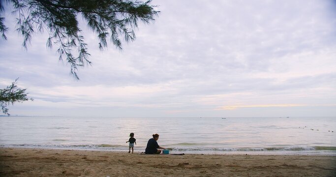 happy Asian family relaxing on a tranquil beach, enjoying the ocean view under a cloudy sky, Multi-generation family enjoy outdoor together at summer travel holiday vacation time - Powered by Adobe