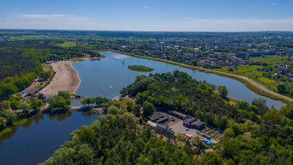 Fototapeta premium beautiful spring and summer day with a view of the lake near the big city, a recreation center with houses and umbrellas, a beautiful sandy beach, water, rest, relaxation, beautiful blue sky