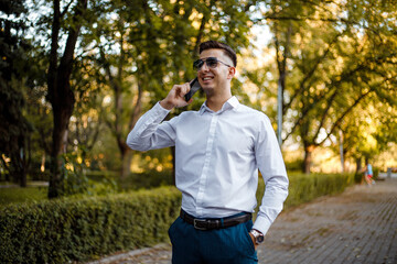 Man in White Shirt and Blue Pants Talking on Cell Phone