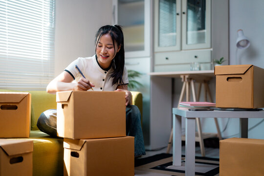 Happy asian woman preparing cardboard boxes for moving to new house