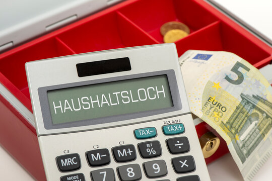 Eine leere Geldkasse und dar&uuml;ber ein Taschenrechner mit der Aufschift: Haushaltsloch