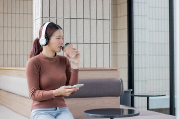 Beautiful asian woman listen to music with headphone in coffee