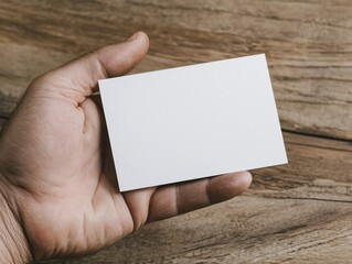 Obraz premium Blank business card in hand on wooden background for identity and branding concepts