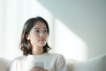 Young Woman Holding Smartphone Indoors.
