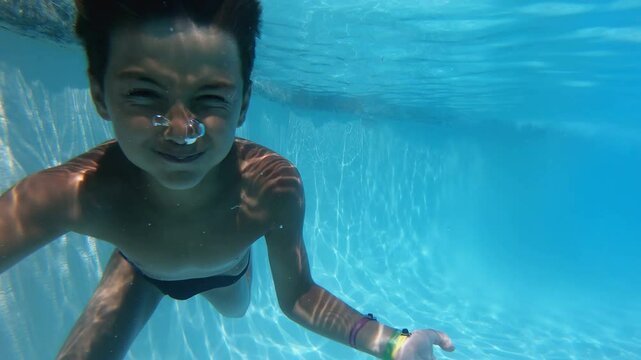 Boy dives into the depths of a blue pool and smiles. Close-up. High quality 4k footage