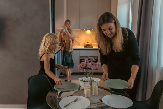 Family Dinner Preparation Kitchen Table Setting: Mothers and daughters setting table for meal. - Powered by Adobe