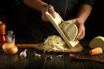Shredding fresh cabbage to prepare a healthy breakfast vegetable dish. The hands of a chef expertly...