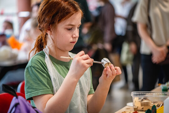 cute teen girl at a master class making a craft from wood, exhibition of crafts, crafts fair, education, master classes