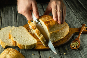 Hands expertly slice a loaf of freshly baked bread on a rustic wooden board. Sunlight gently...