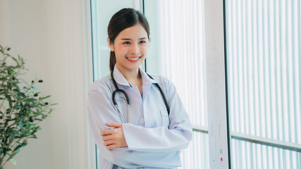 A doctor in a white lab coat is holding a stethoscope and smiling.