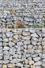 Abstract background of granite stones and wire mesh in a gabion wall