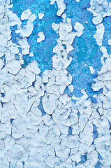 Peeling paint background, flakes paint of light blue color on the old rough concrete wall, texture of peeling paint