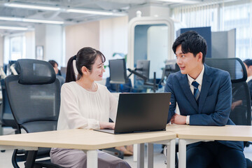 先輩社員から業務を教えてもらう新人の女性