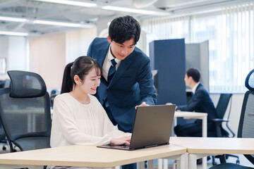 先輩社員から業務を教えてもらう新人の女性