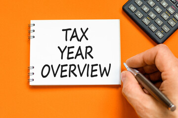 Tax year overview symbol. Concept words Tax year overview on beautiful white note. Beautiful orange background. Black pen. Businessman hand. Business tax year overview concept. Copy space.