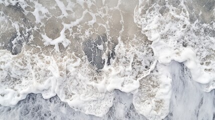 Fototapeta premium Ocean waves crashing onto the shore creating foamy textures