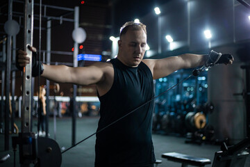 Man Working Out With Cable Machine At Night In Fitness Center