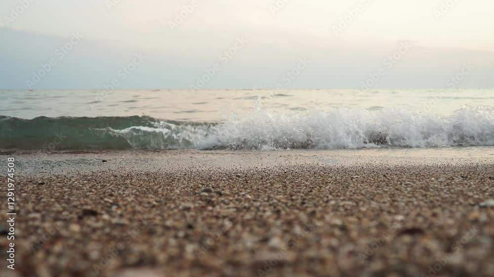 Poster Soft waves roll onto a sandy beach as twilight sets in. The calm sea reflects the fading light, creating a serene atmosphere for evening relaxation. Reflection of pink rays. Mediterranean Adriatic Sea