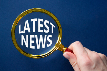 Latest News symbol. Concept word Latest News on magnifying glass. Businessman hand. Beautiful deep...