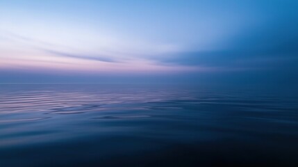 Obraz premium Photograph of a vast body of water. the water is calm and still, reflecting the colors of the sky. the sky is a deep blue with a few wispy clouds scattered across it.