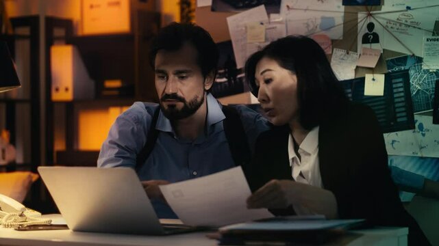 Male and female detectives discuss crime video evidence, searching for new leads