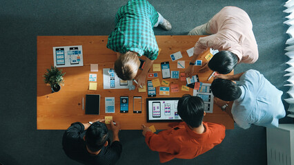 Top down view of business team writing idea on sticky note while planing for Ux Ui design for mobile phone interface. Group of creative designer working on wireframe prototype design. Convocation. © InfiniteFlow