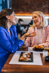 Smiling lesbian couple talking to each other at restaurant.
