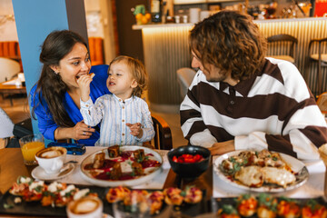 Family of three eating in a restaurant delicious food. Food and drink concept.