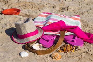 Different accessories for relax on sand. Straw hat, slippers and towel. Summer time on beach