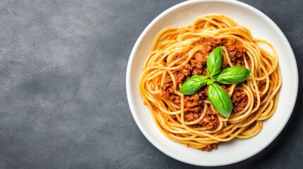 Delicious spaghetti bolognese garnished with fresh basil on a dark marble surface.
