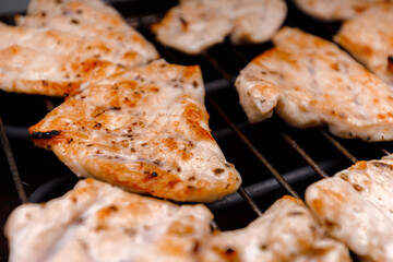 Grilled chicken fillets on a barbecue grill during summer cookout