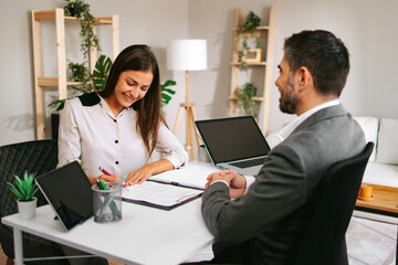 Happy businesswoman signing contract after successful job interview with businessman
