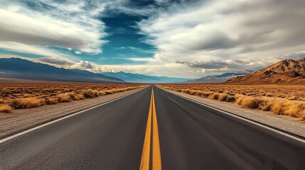 Explore the endless desert road under a dramatic sky and mountains, inviting you on an adventurous journey. Perfect as a backdrop for your designs.