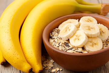 Ripe bananas next to a bowl of sliced bananas & oats, on a wood surface, for breakfast