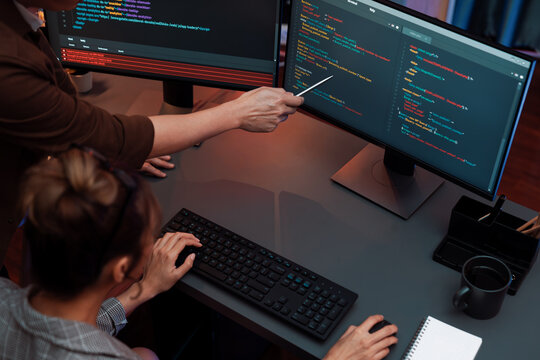 Top view of IT developers discussing with point to intelligent website development coder system running data online two screens information technology at neon light room at modern office. Infobahn.