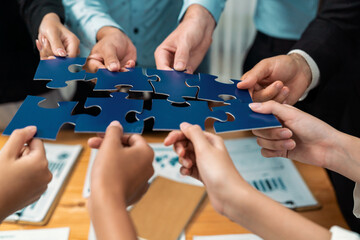 Multiethnic business people holding jigsaw pieces and merge them together as effective solution solving teamwork, shared vision and common goal combining diverse talent. Meticulous