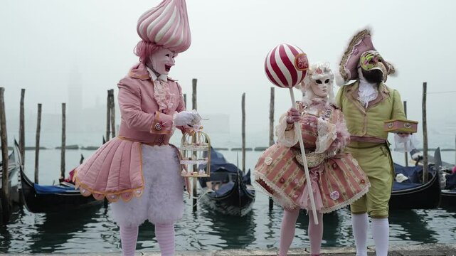 Venice, Italy - People dressed in carnival masks are photographed by tourists in the scenery of the ancient Venetian palaces