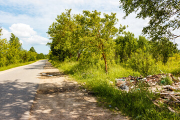 Roadside with illegal construction waste dump in the grass