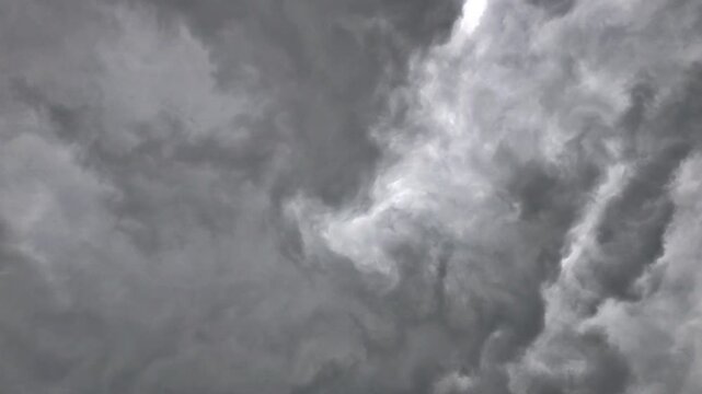 Ominous, dark, storm clouds swirl and rotate to possibly form a funnel cloud.