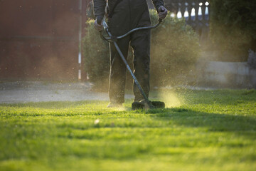 Garden worker with lawn mover. Garden works in spring.
