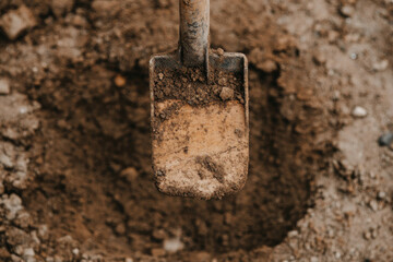 A shovel is stuck in the ground in a dirt area