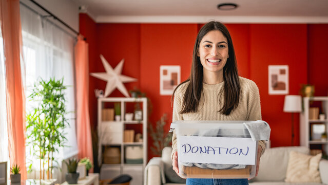 portrait of young woman stand and hold box with clothes for donation
