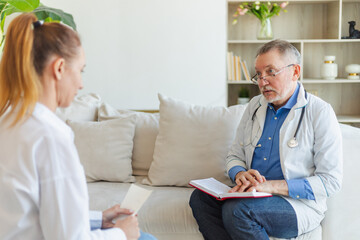 Senior man doctor examining young woman in doctor office or at home. Girl patient and doctor have...