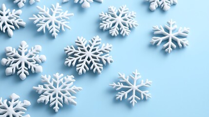 White snowflakes scattered on a light blue surface, creating a winter background, ideal for holiday designs