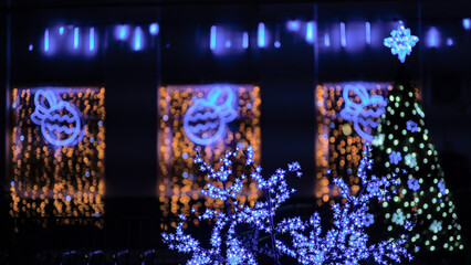 A street is lit up with Christmas lights and decorated with light trees and branches. Christmas and...