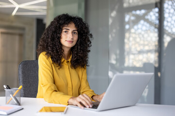 Businesswoman is serious and confident at her workplace inside the office. The woman is looking at...
