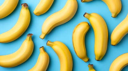 Yellow bananas scattered on blue background, top view, for healthy eating and food design