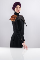 A stylish Muslim woman in a hijab presents her innovative handmade fashion accessory crafted from...