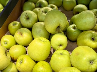 A vibrant and colorful display of fresh, crisp green apples organized neatly in a bustling market settings. Close-up