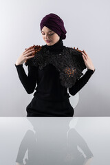 A stylish Muslim woman in a hijab presents her innovative handmade fashion accessory crafted from...